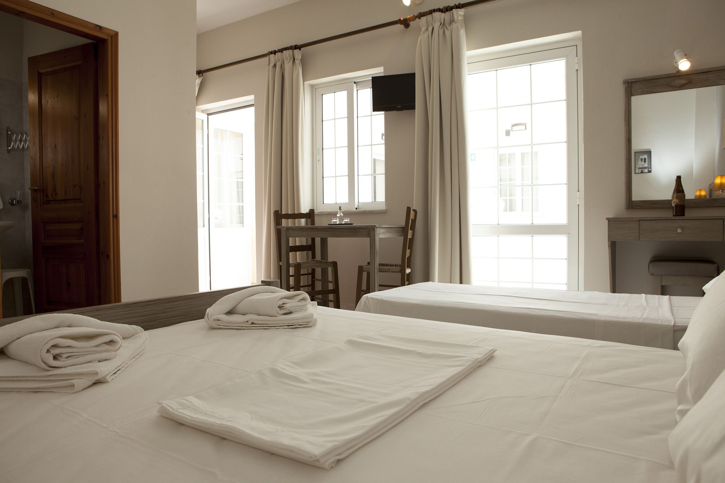 Ein Hotelzimmer mit zwei Betten, einem Schreibtisch, einem Stuhl, einem Fernseher und einem Badezimmer.