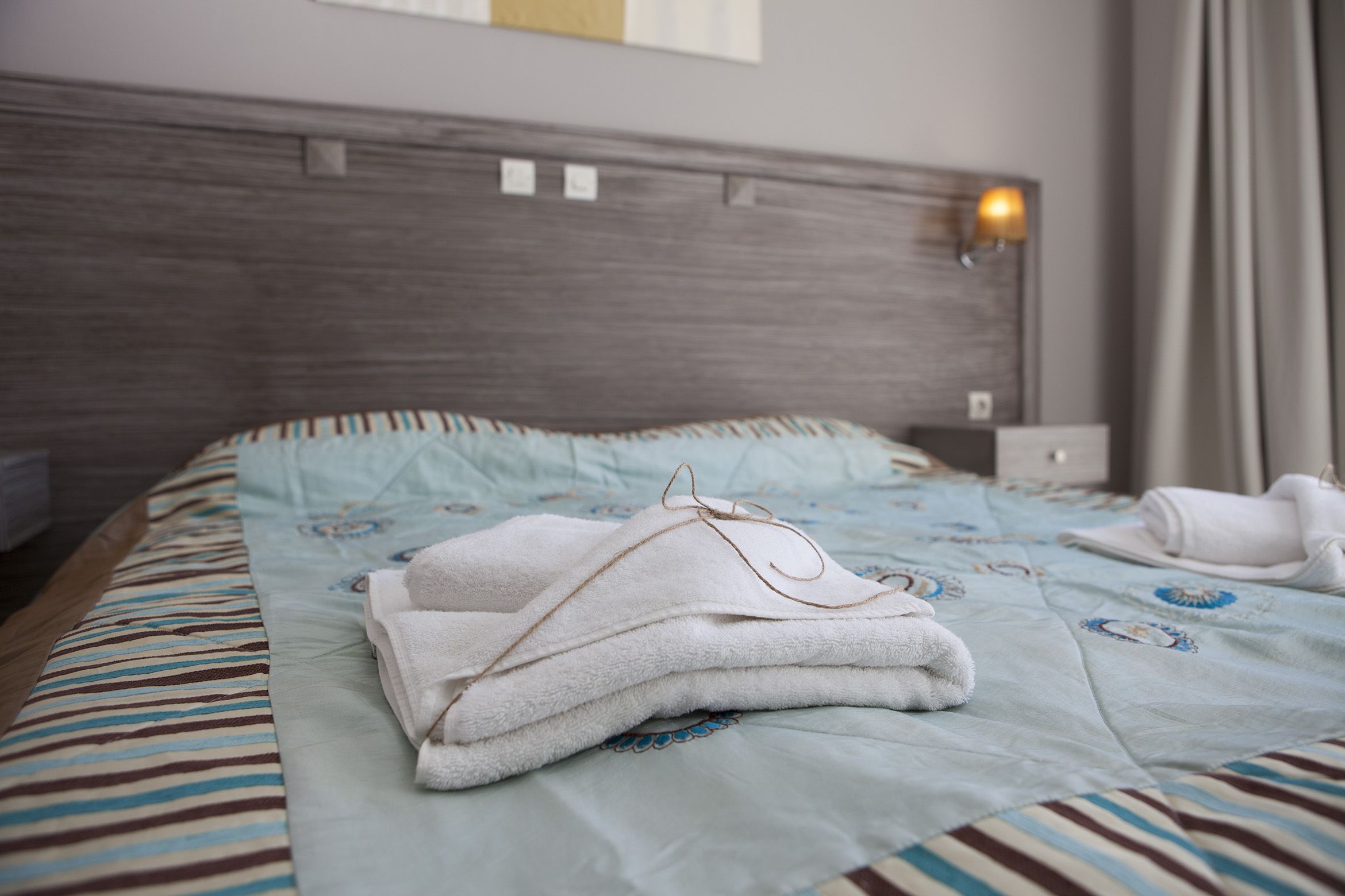 A neatly made bed with a striped bedspread and a folded towel on top.