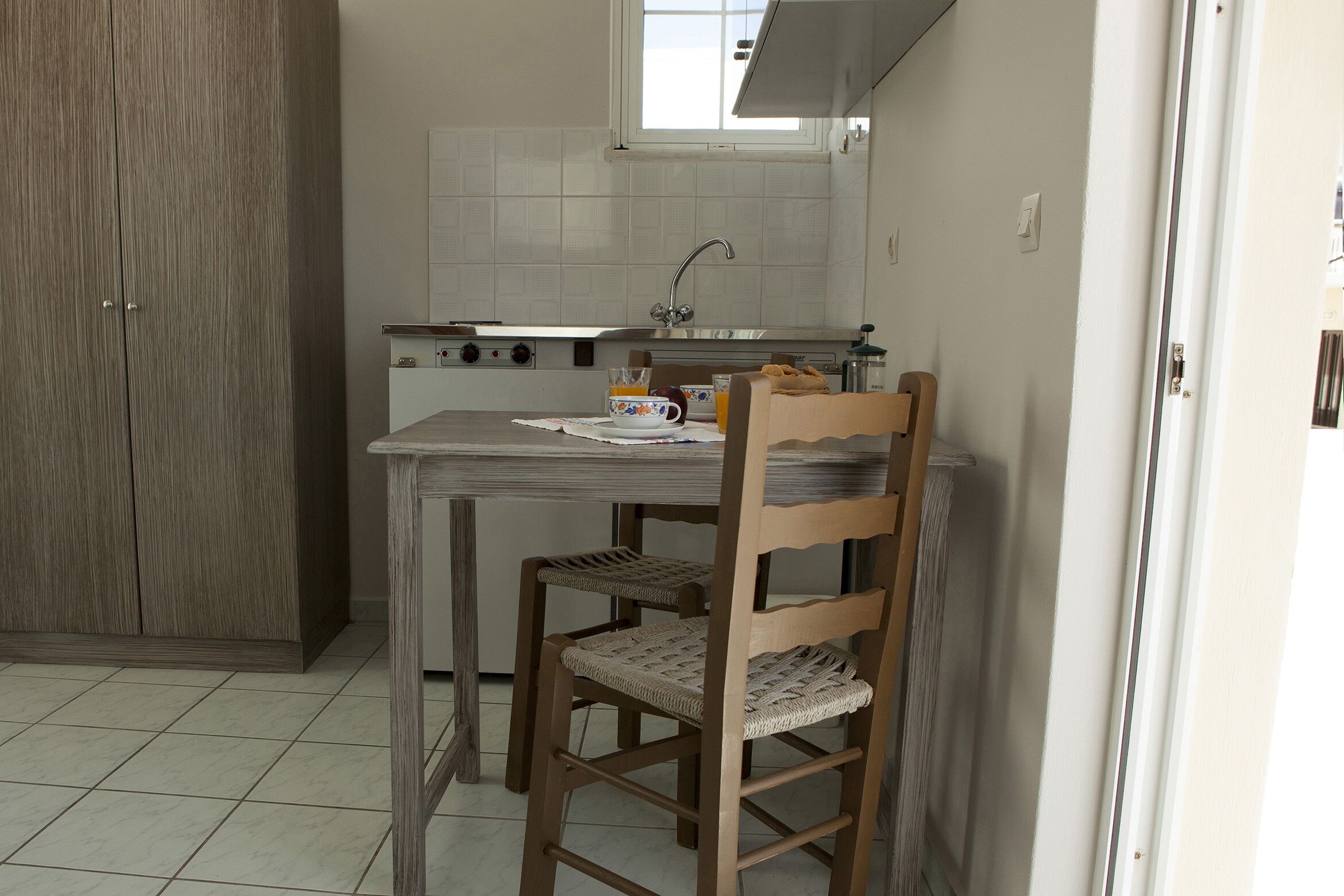 A compact kitchen with a dining table, chairs, and a window above the sink.