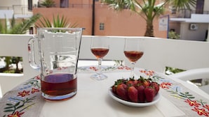 Un tavolo con una caraffa di tè, due bicchieri da vino e un piatto di fragole.