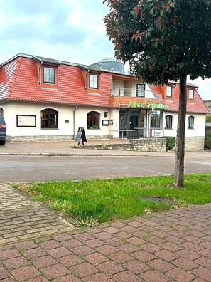 A two-story building with a red-tiled roof, a signboard, and a paved walkway.