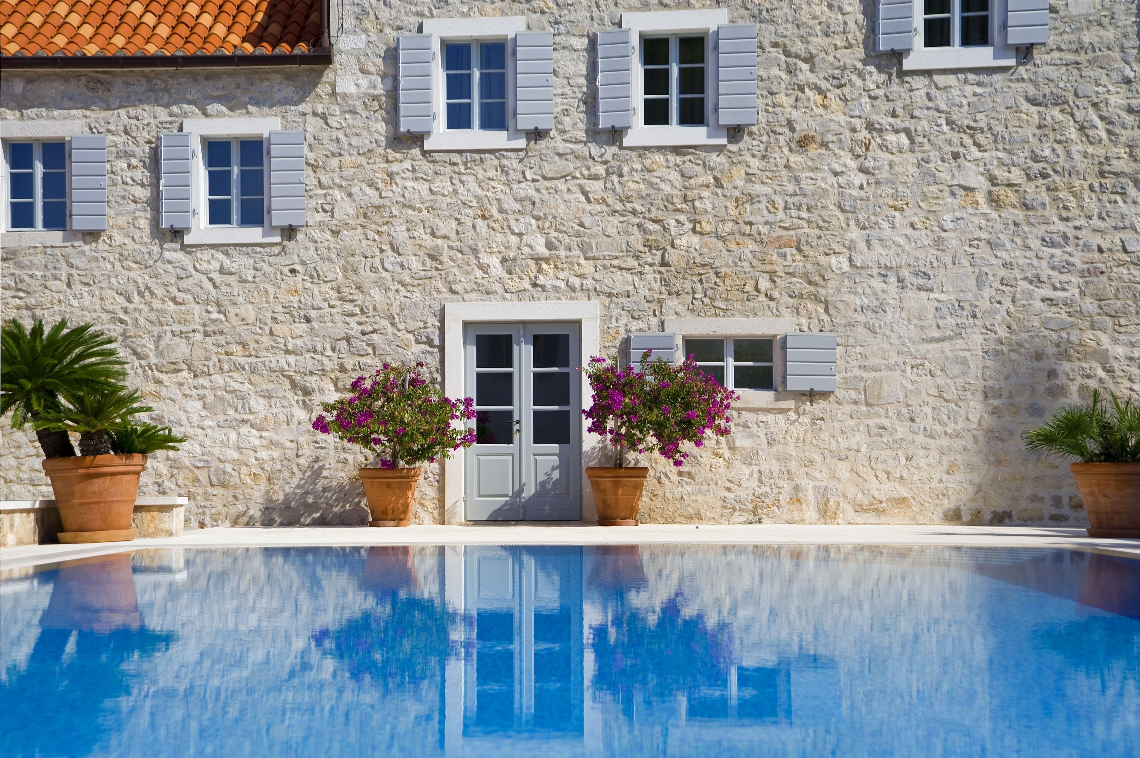 Un edificio de piedra con una piscina delantera.