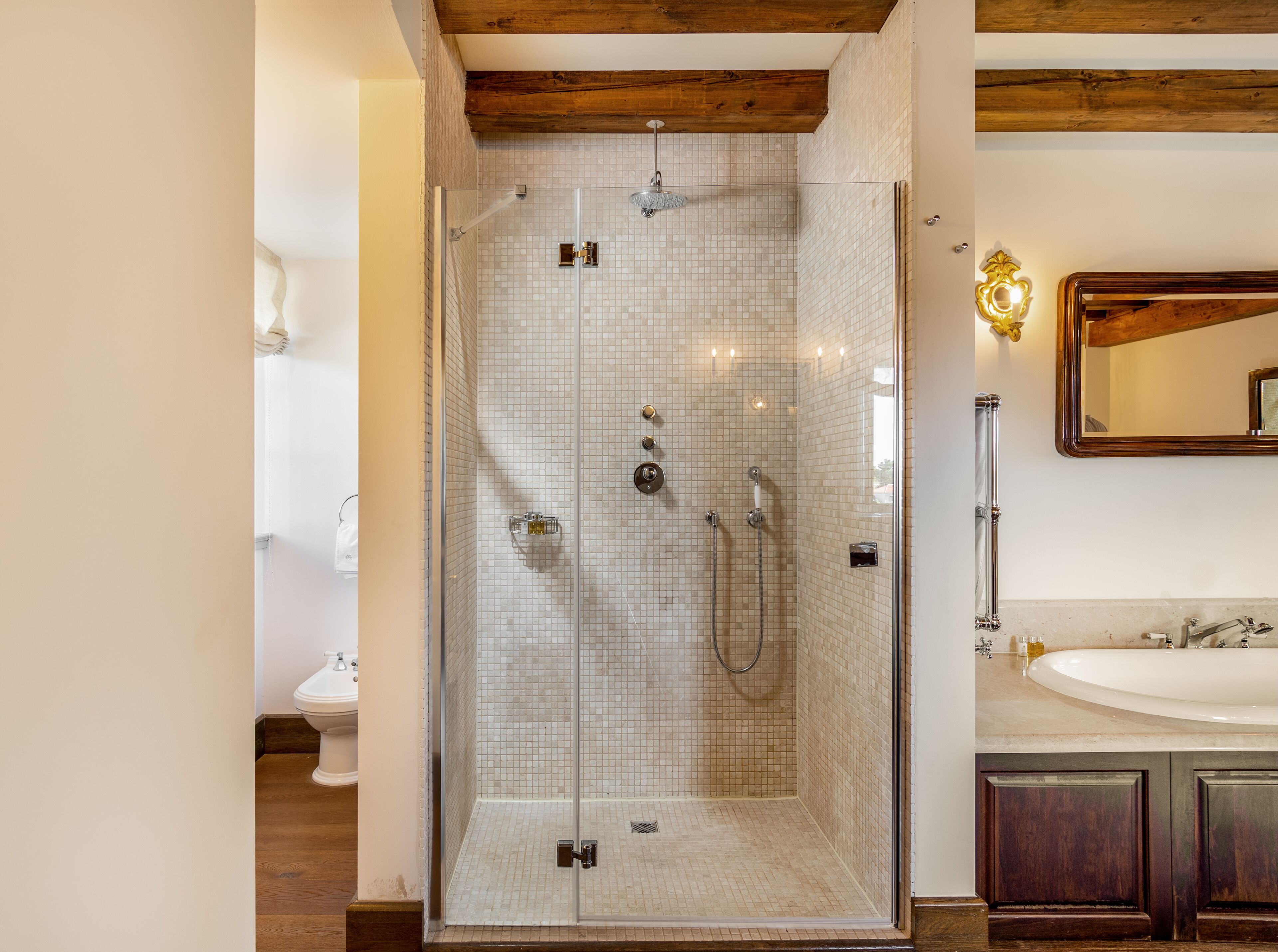 Une salle de bain moderne avec une douche à parois de verre, un plafond en bois et un grand miroir au-dessus du lavabo.