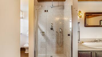 Une salle de bain moderne avec une douche à parois de verre, un plafond en bois et un grand miroir au-dessus du lavabo.