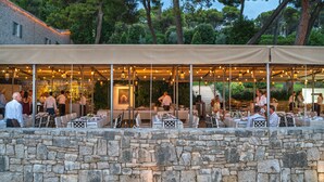 Un restaurant en plein air avec des murs en pierre, des tables et des chaises disposées sous une tonnelle.