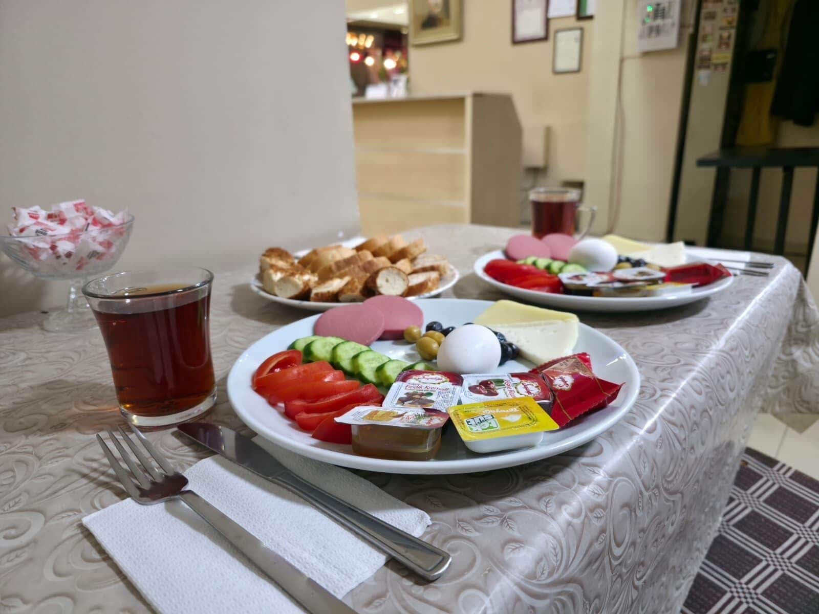A dining table with plates of food, a glass of tea, and a fork.