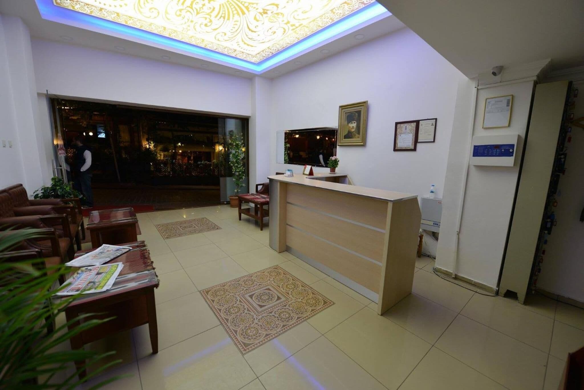 A hotel lobby with a reception desk, seating area, and a decorative ceiling light.