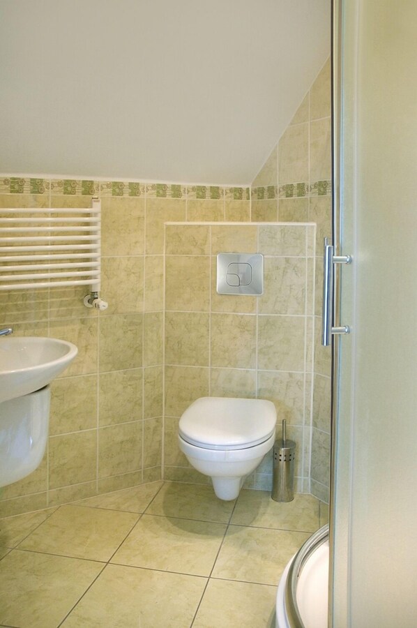 A bathroom with a toilet, sink, and shower area.