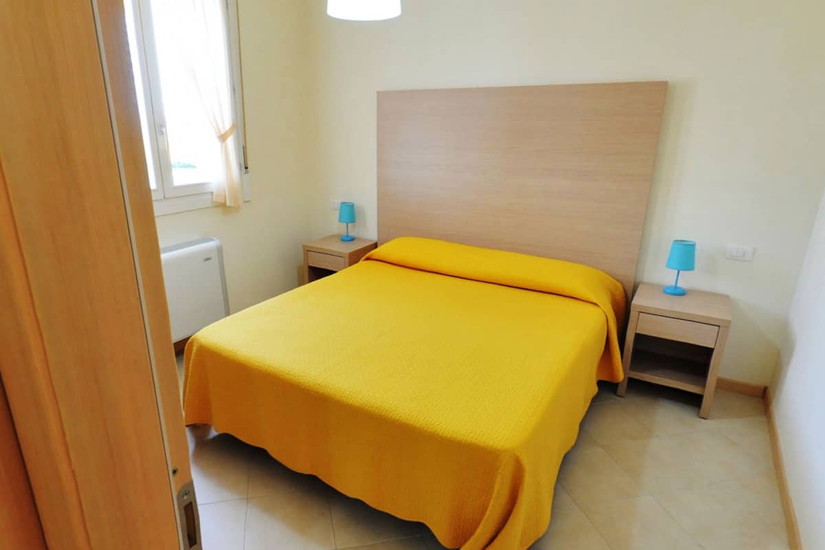 A bedroom with a bed, two bedside tables, and a window with curtains.