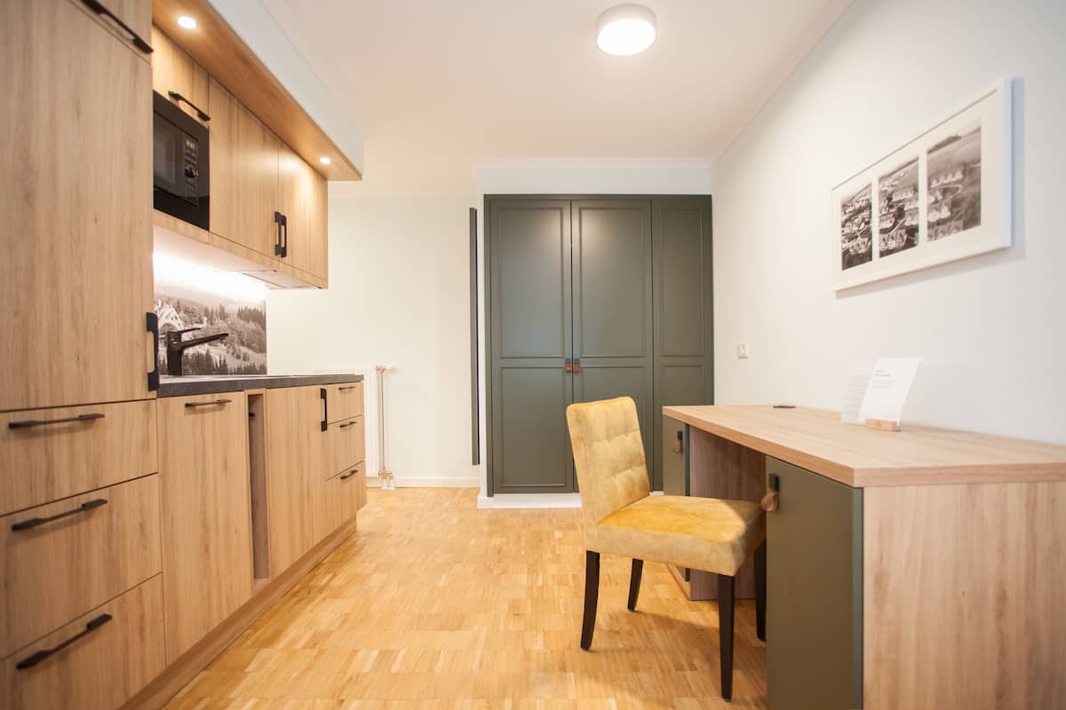 A modern kitchen with wooden cabinets, a built-in microwave, and a wooden countertop.