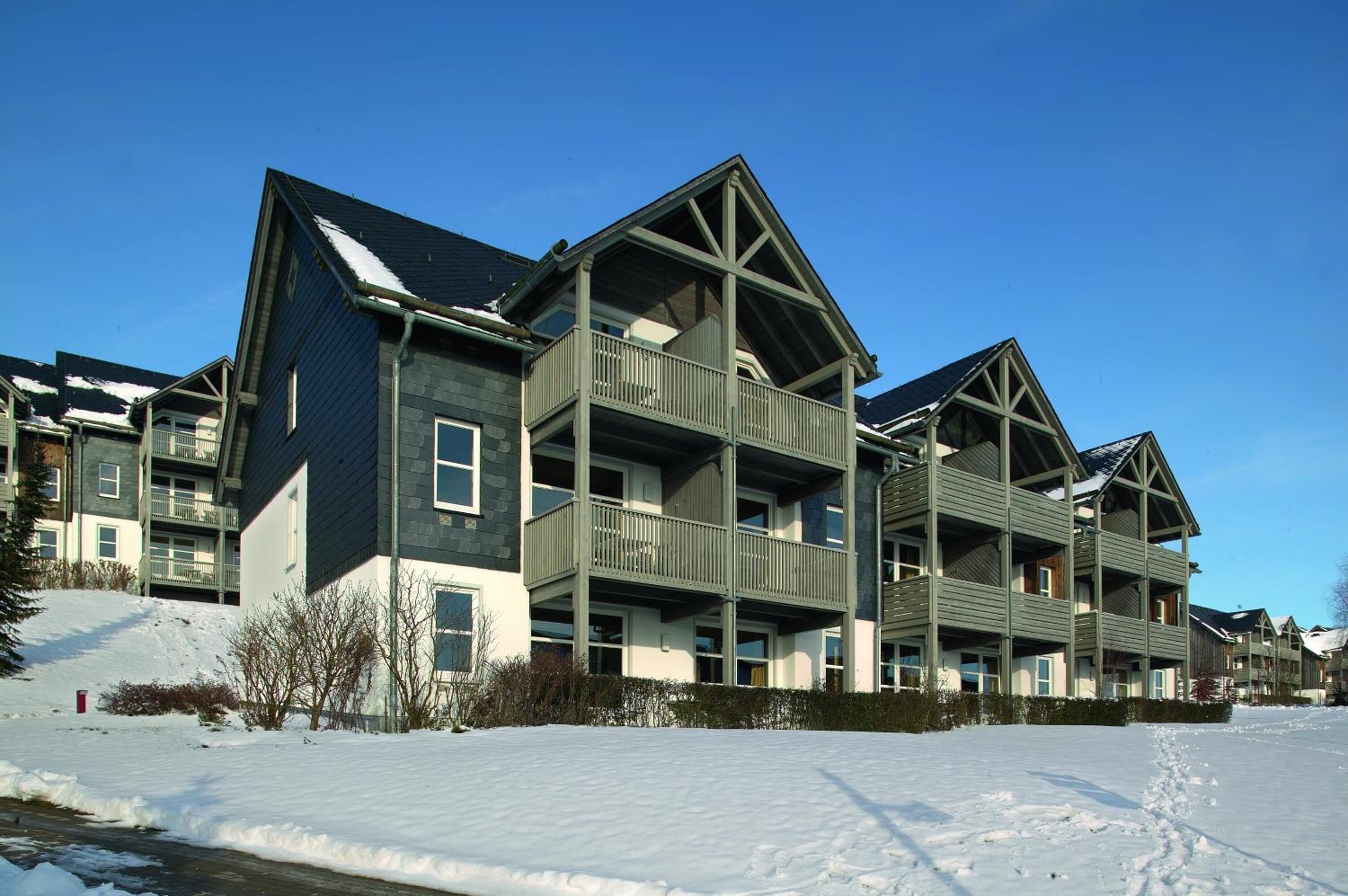 A multi-story building with balconies and a snow-covered ground.