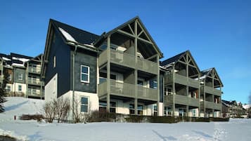 Un edificio de varios pisos con balcones y el suelo cubierto de nieve.