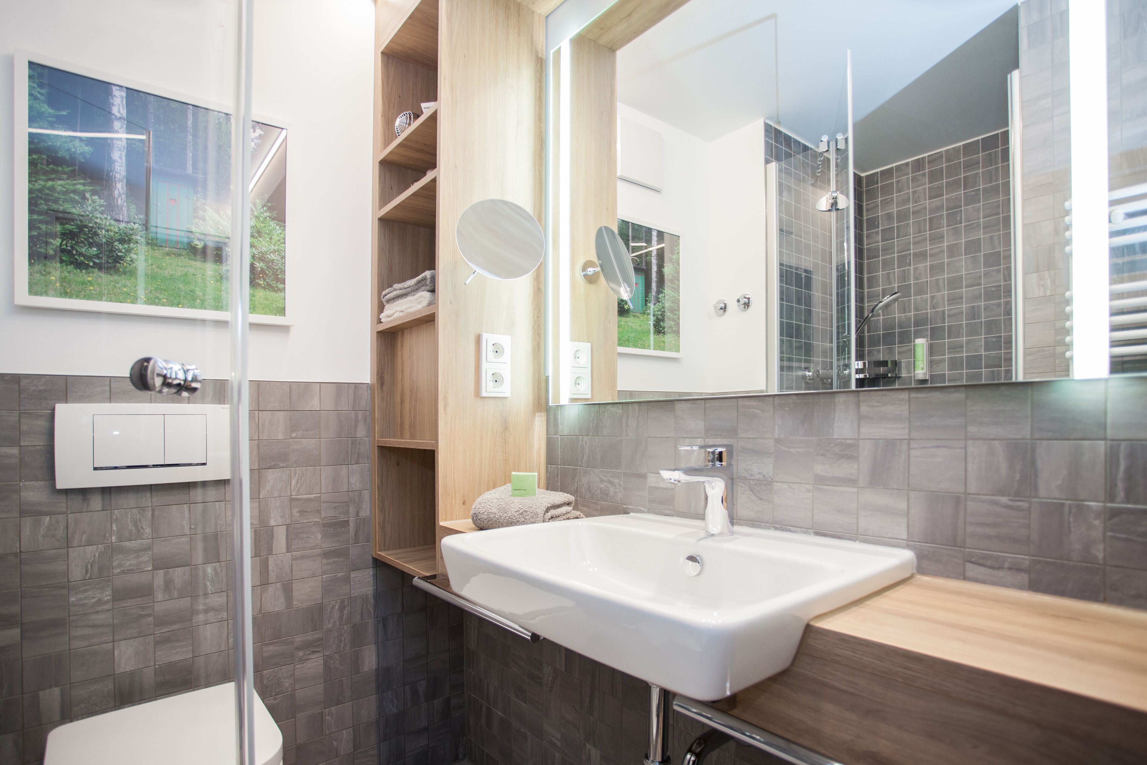 A modern bathroom with a large mirror, a white sink, and a shower area.