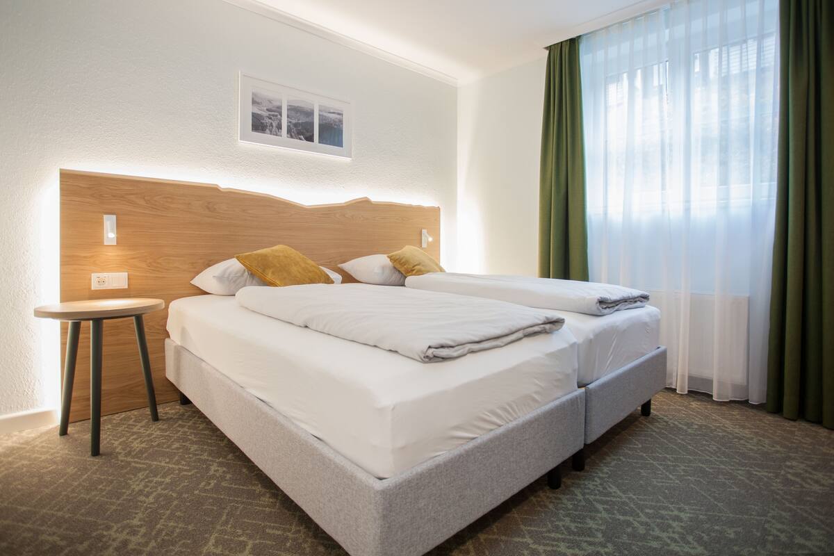 A hotel room with a large bed, a small table, and a picture on the wall.