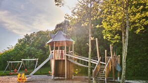 A wooden play structure with slides and swings in a park. - Hapimag Resort Winterberg (Winterberg)