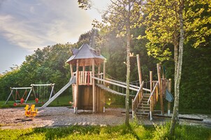 Una estructura de juego de madera con toboganes y columpios en un parque.