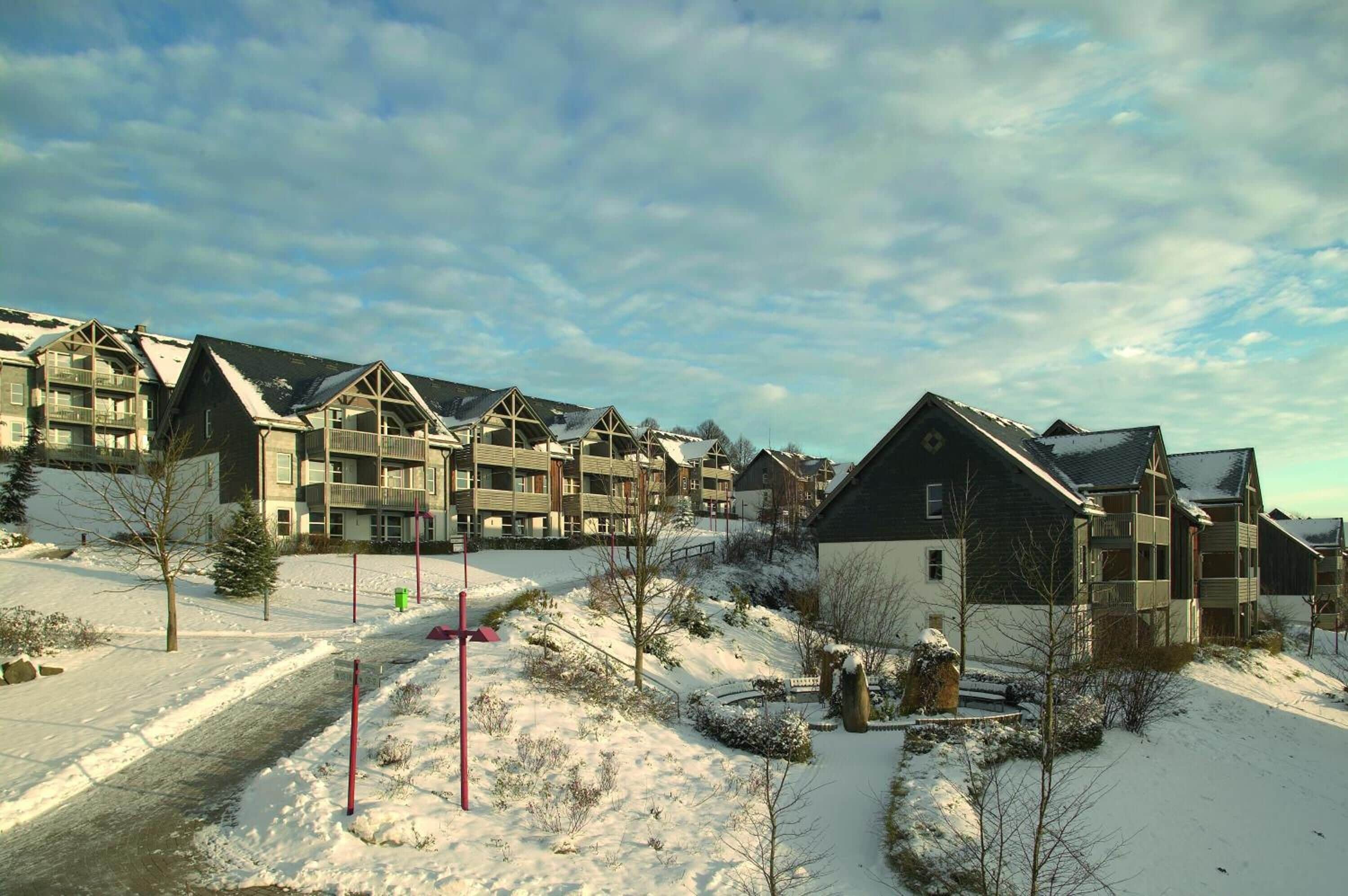 Zona residencial con edificios de varios pisos, paisaje cubierto de nieve y cielo despejado.