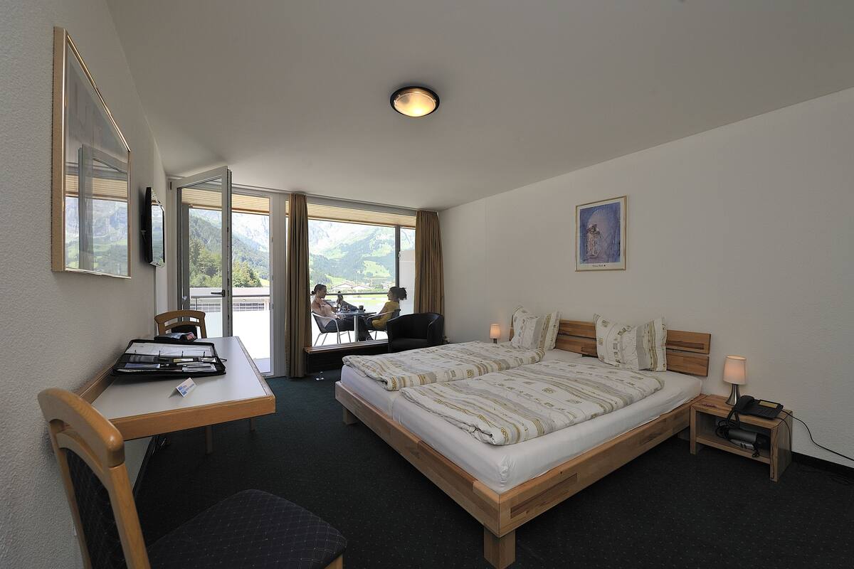 Una habitación de hotel con cama, escritorio, silla y vistas al exterior.