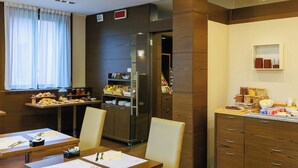 A hotel dining area with a buffet setup, wooden cabinetry, and a refrigerator.