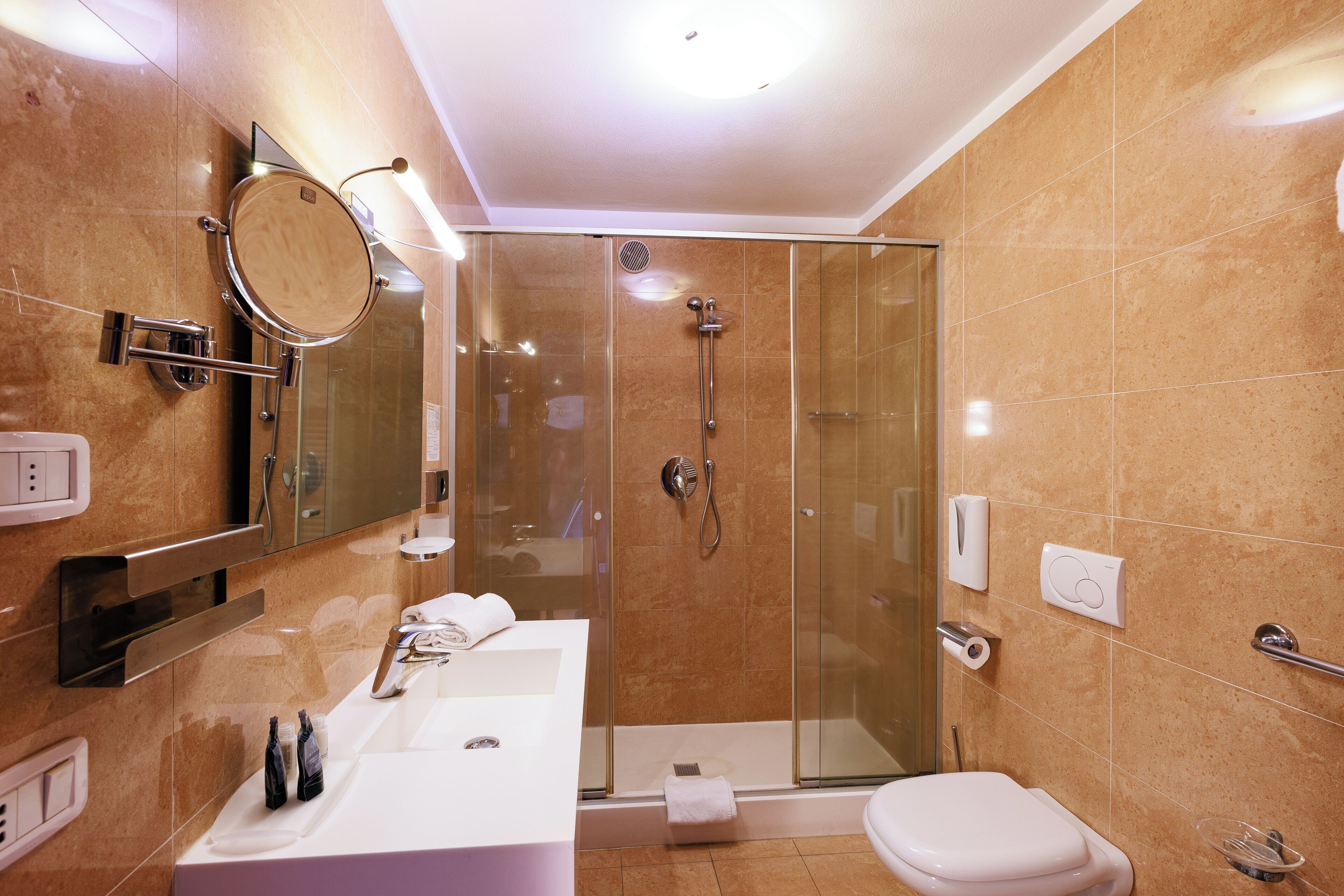 Un bagno moderno con doccia vetrata, lavandino bianco e servizi igienici.