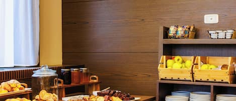 A breakfast buffet with various pastries, fruits, and beverages.