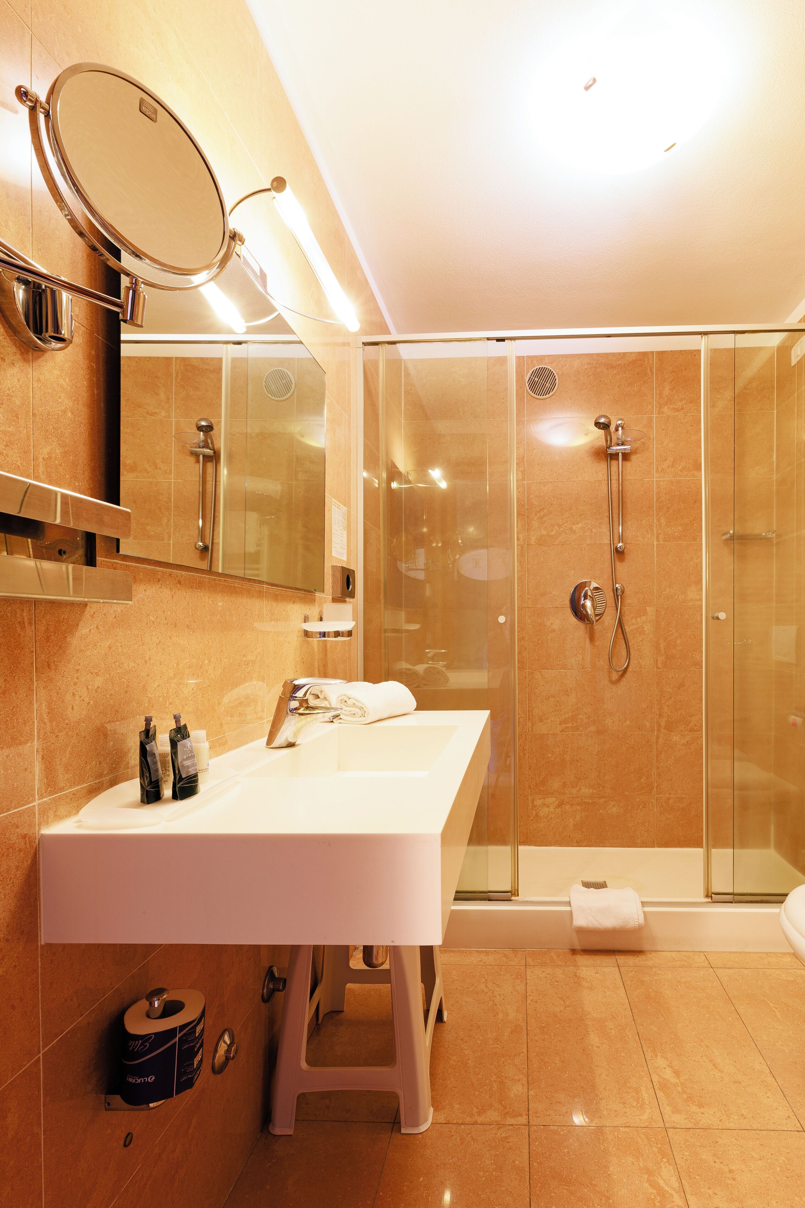 A modern bathroom with a large mirror, a sink, and a glass-enclosed shower.