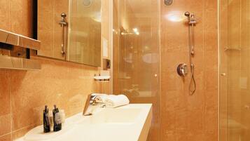 A modern bathroom with a large mirror, a sink, and a glass-enclosed shower.