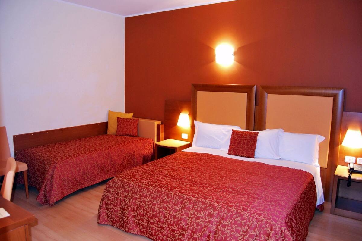 Een hotelkamer met twee eenpersoonsbedden, een houten hoofdbord, nachtkastjes en een stoel.