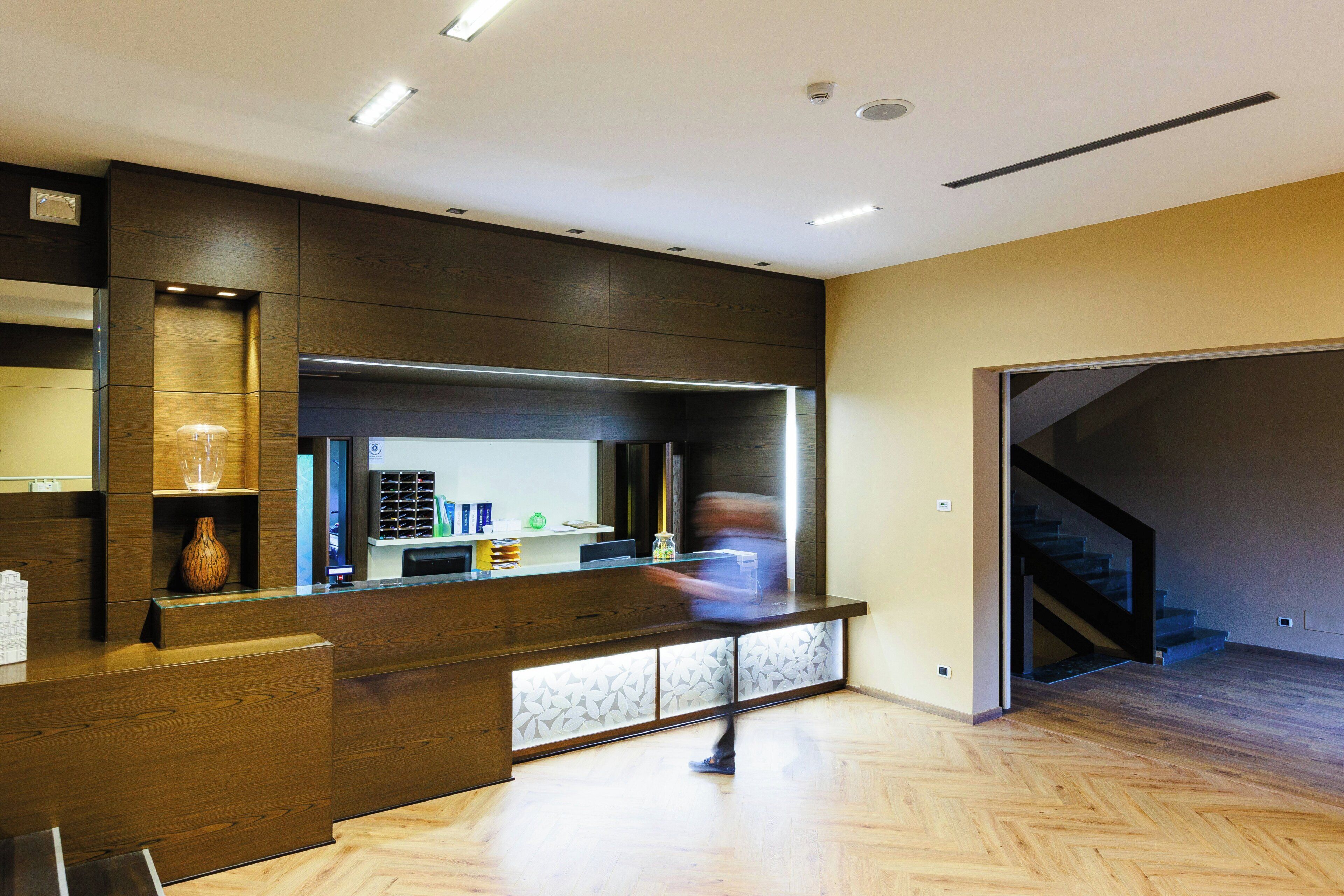 A modern reception area with a wooden counter, a glass vase, and a staircase leading to an upper level.