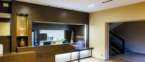 A modern reception area with a wooden counter, a glass vase, and a staircase leading to an upper level.