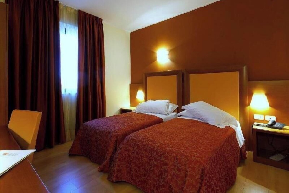 Une chambre d’hôtel avec deux lits, un bureau et une chaise.