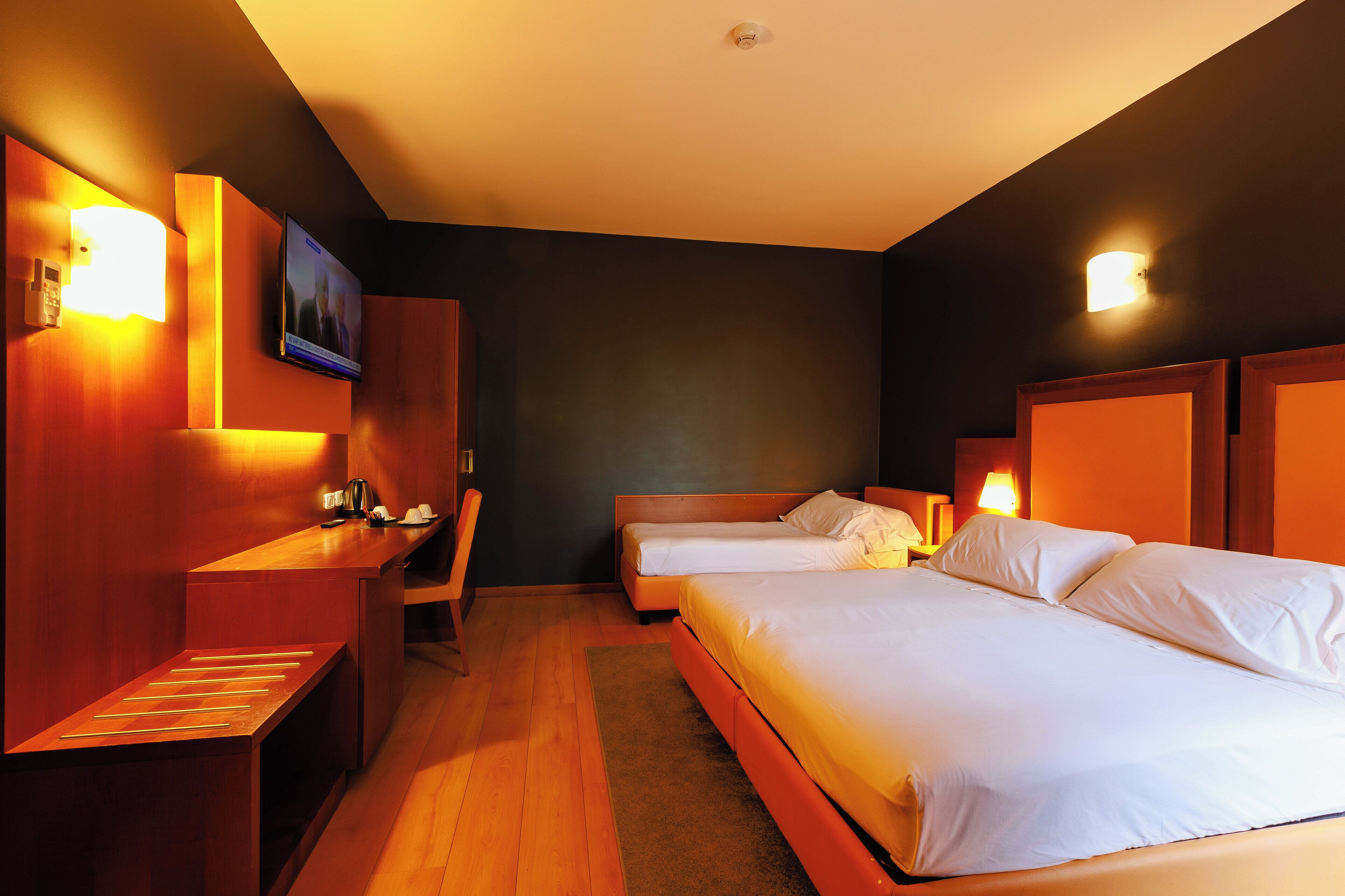 A hotel room with two beds, a desk, and a television.
