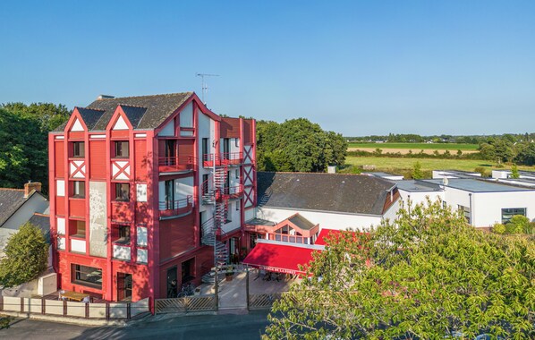A red multi-story building with a balcony and a staircase. - Auberge de la Foret (Le Gavre)