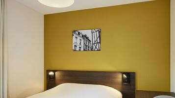 Habitación de hotel con una cama, una mesa y una silla. Hay un cuadro en la pared sobre la cama.