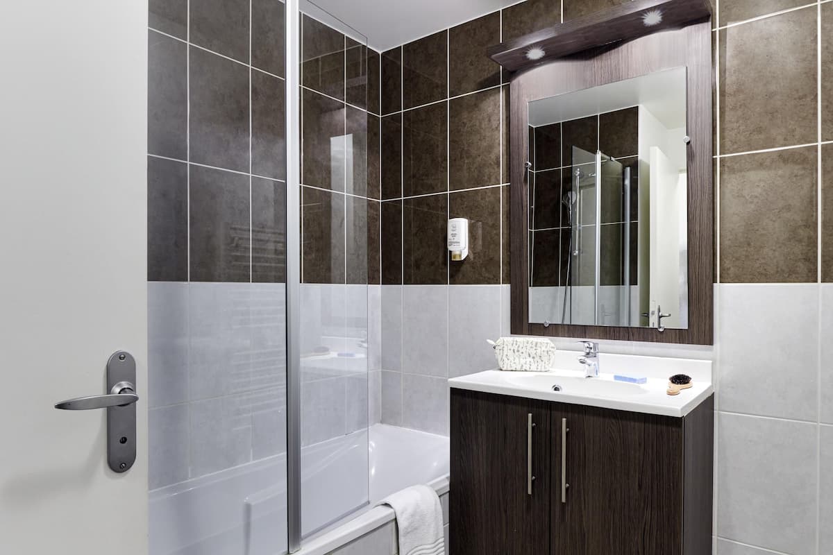 A modern bathroom with a shower, a sink, and a mirror.