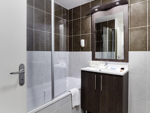 Un baño moderno con ducha, lavabo y espejo.