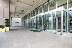 A modern building with a glass entrance, a tiled floor, and a ceiling with recessed lighting.