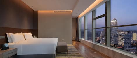 Une chambre d’hôtel moderne avec un grand lit, une table de chevet et une vue sur le paysage urbain.