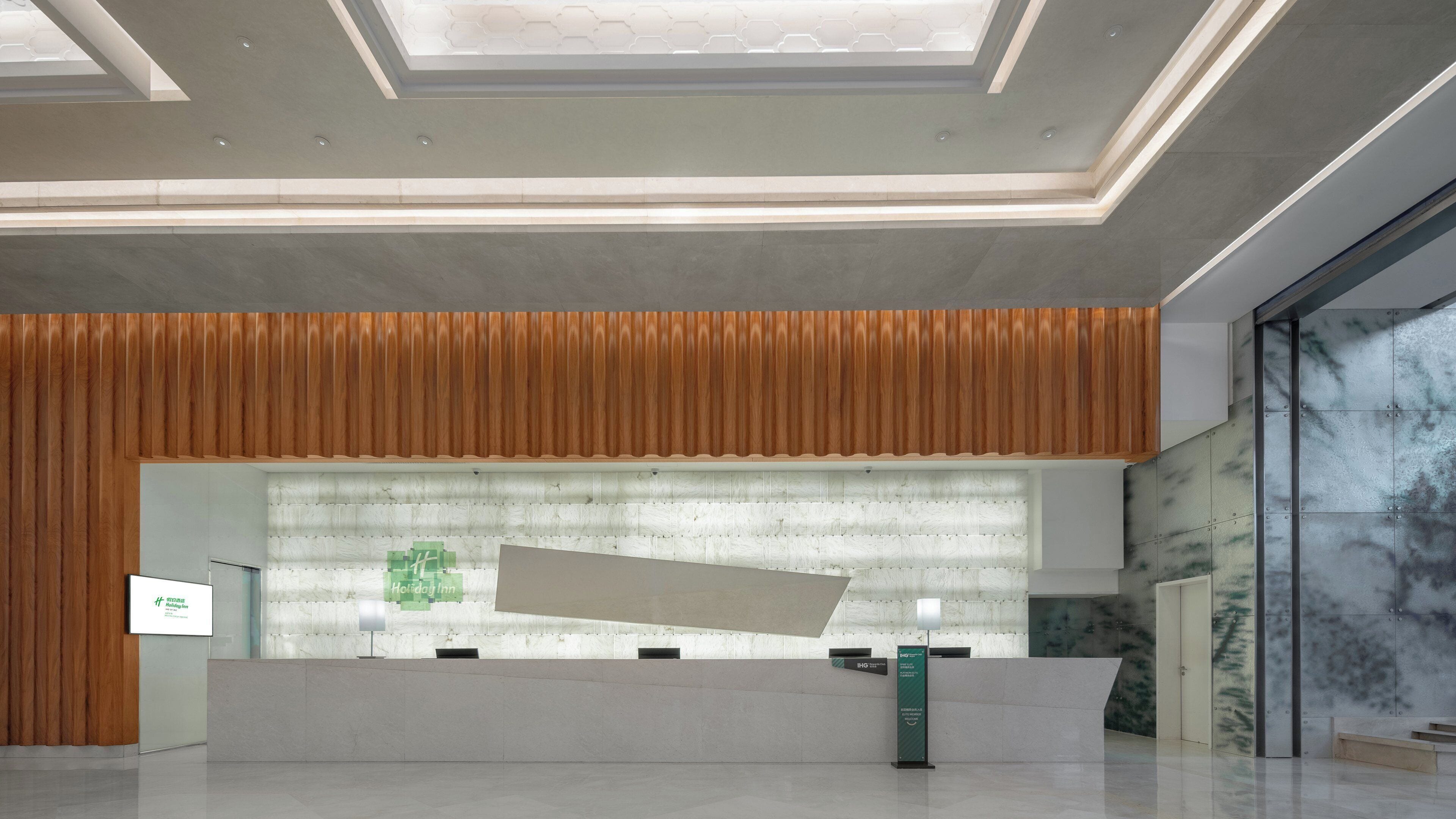 A reception area with a modern design, featuring a reception desk, a wooden panel wall, and a glass partition.
