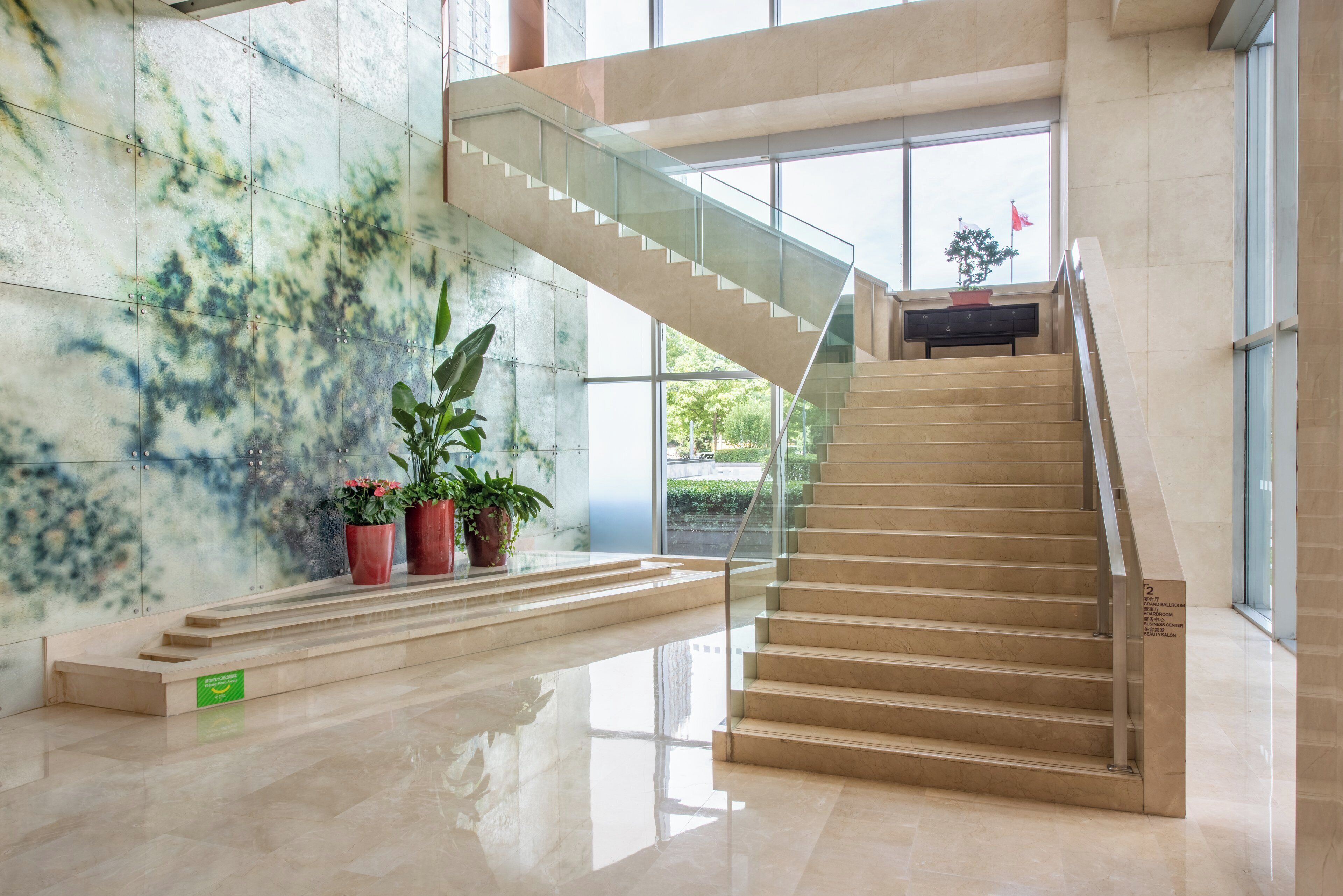 Een modern interieur met een trap, potplanten en een glazen balustrade.