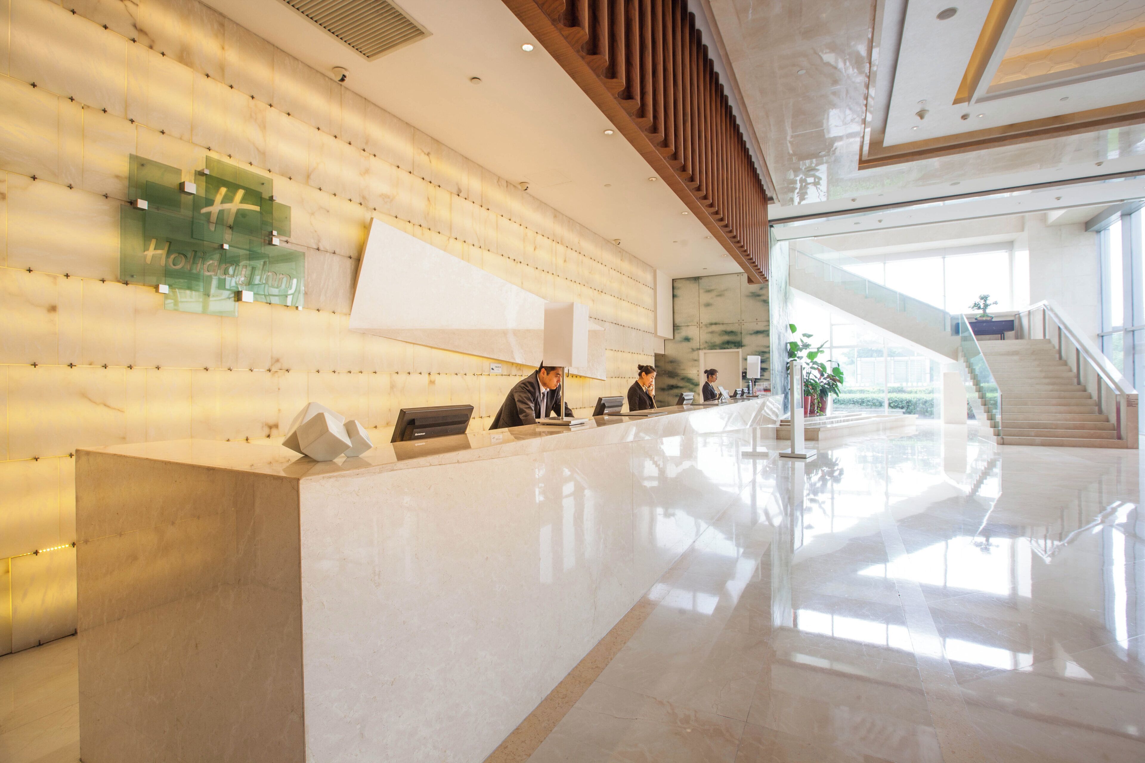 A reception area with a marble counter, a glass display case, and a staircase leading to an upper level.