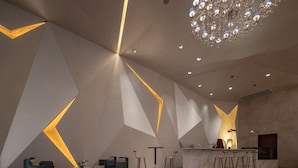 A modern interior with geometric wall designs, a bar area, and a chandelier. - Holiday Inn Beijing Focus Square by IHG (Beijing)