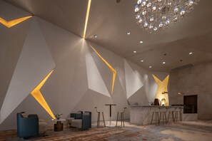 Un interno moderno caratterizzato da motivi geometrici sulle pareti, un'area bar e un lampadario.