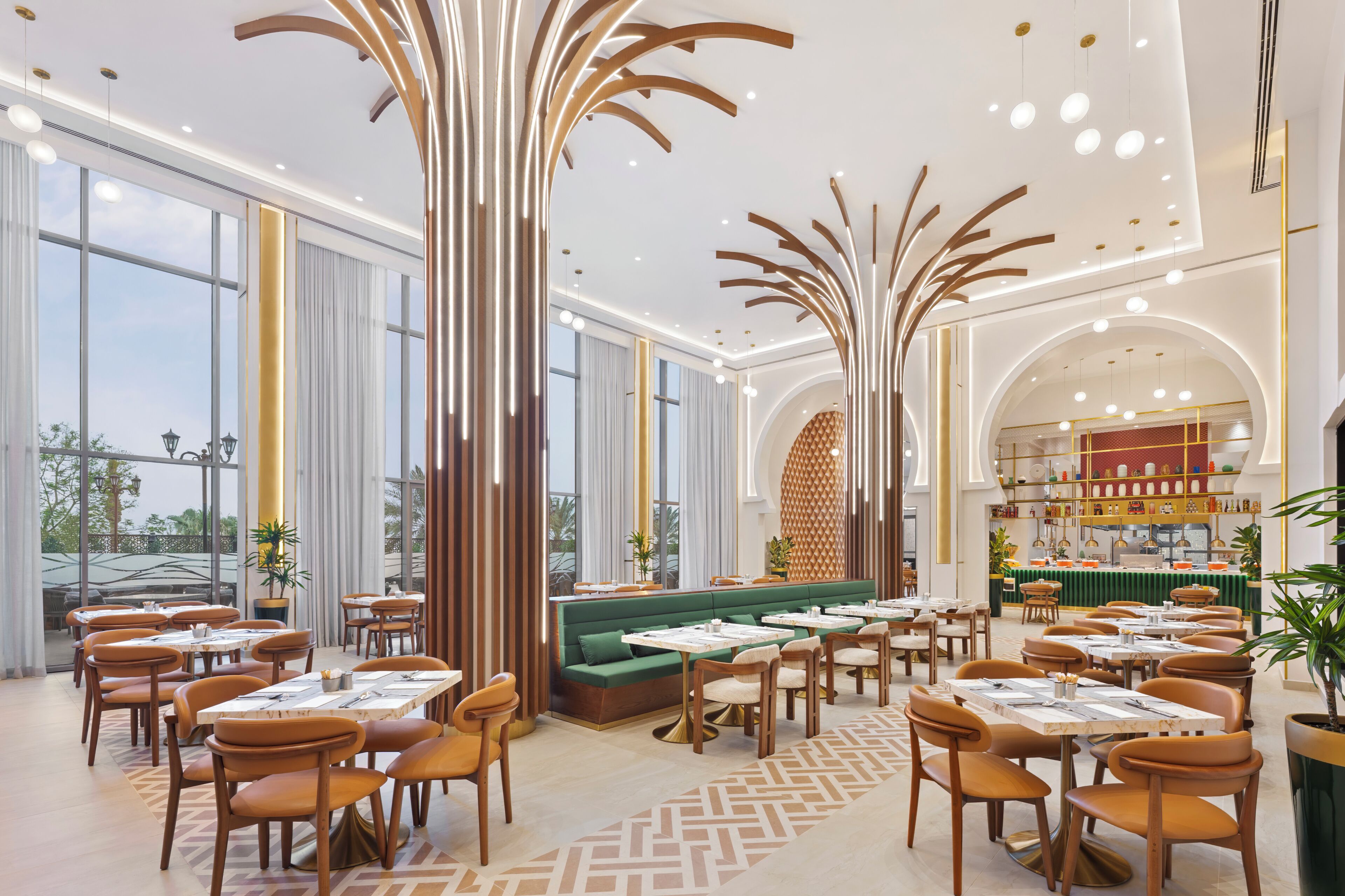 Un interno ristorante moderno con soffitti alti, illuminazione a sospensione e una zona salotto centrale.