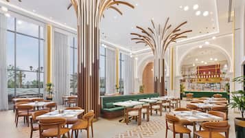 Un interno ristorante moderno con soffitti alti, illuminazione a sospensione e una zona salotto centrale.