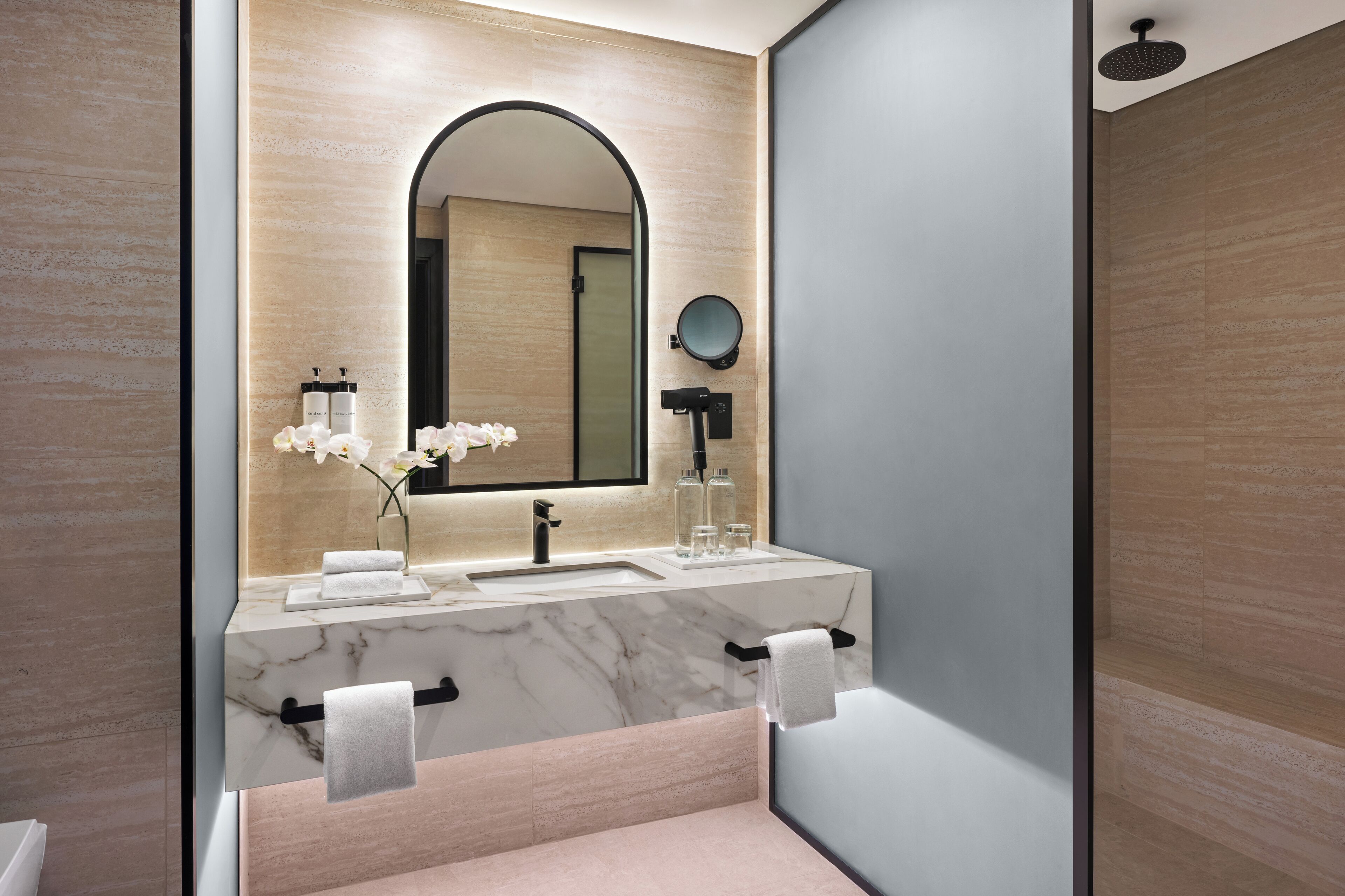 Une salle de bain moderne avec un lavabo en marbre, un grand miroir et une douchette à main.