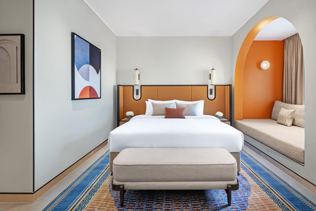 Ein Hotelzimmer mit einem großen Bett, einer Couch, einem kleinen Tisch mit einer Vase und einem Gemälde an der Wand.