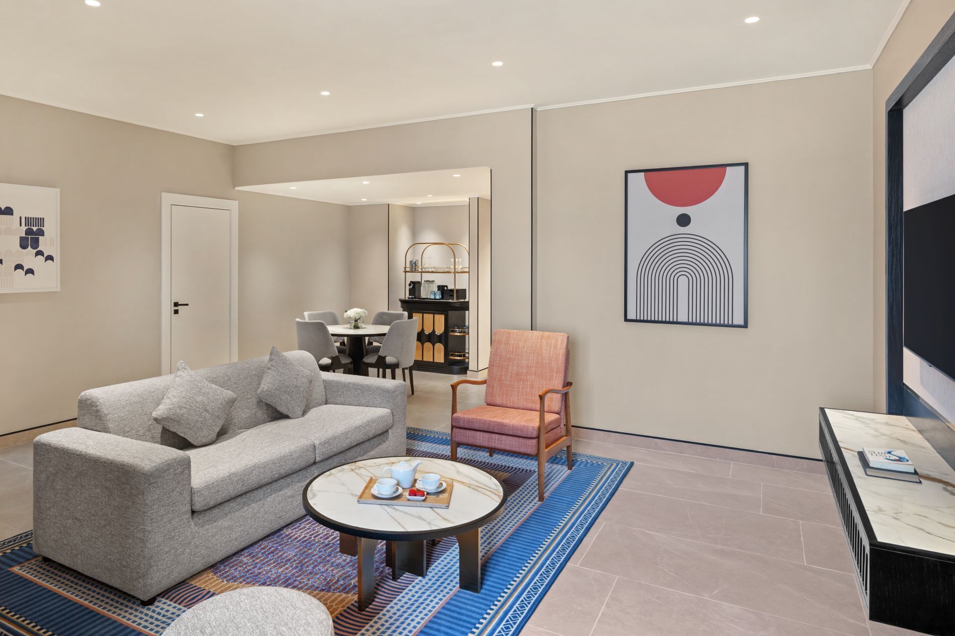 A modern living room with a sofa, armchair, coffee table, and artwork.