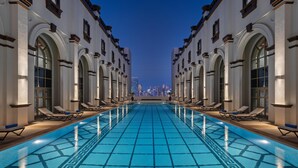 A pool area with lounge chairs and a view of the city skyline at dusk.