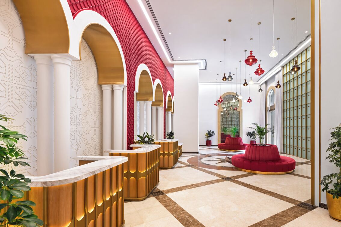 Eine Hotelhalle mit Rezeption, Sitzbereichen und einer Wandgestaltung.